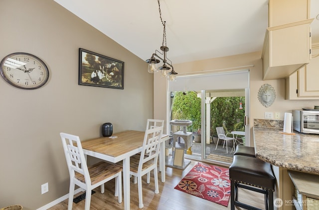 dining space with vaulted ceiling, a toaster, baseboards, and light wood-type flooring