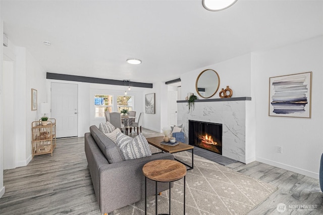 living room with a premium fireplace, wood finished floors, and baseboards