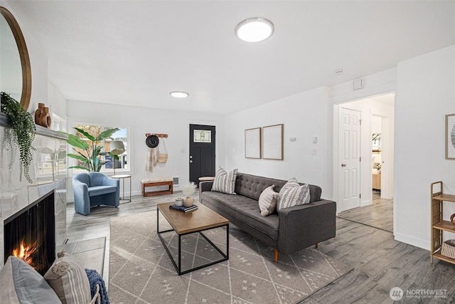 living area with a fireplace, baseboards, and wood finished floors