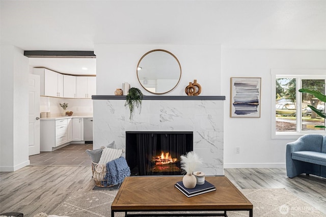 living room with light wood-type flooring, a fireplace, and baseboards