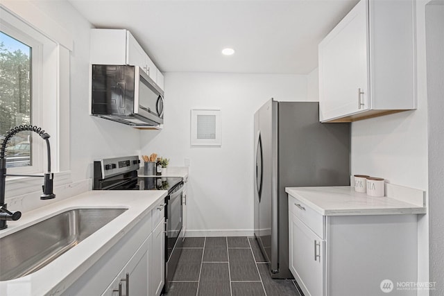 kitchen with stainless steel appliances, recessed lighting, white cabinetry, a sink, and baseboards