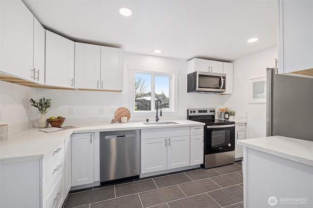 kitchen with appliances with stainless steel finishes, recessed lighting, white cabinetry, and a sink