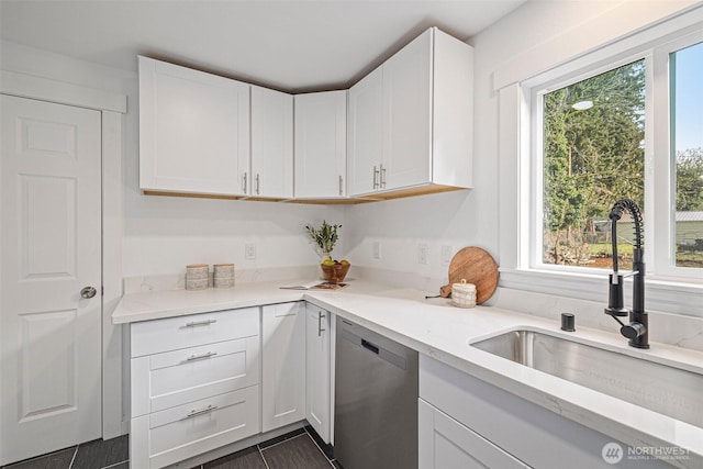 kitchen with stainless steel dishwasher, a sink, and white cabinetry