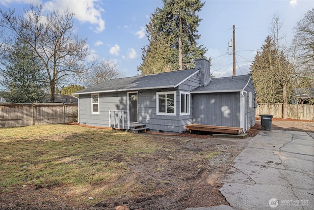 rear view of property featuring a yard, a chimney, a shingled roof, crawl space, and fence private yard