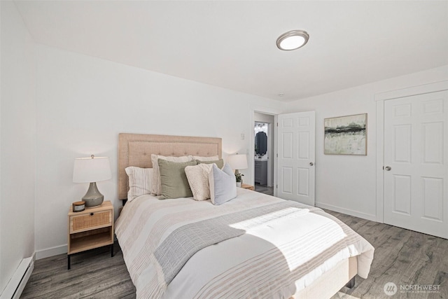 bedroom featuring a baseboard heating unit, baseboards, and wood finished floors