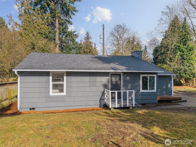 rear view of house with a chimney, a shingled roof, a lawn, crawl space, and fence