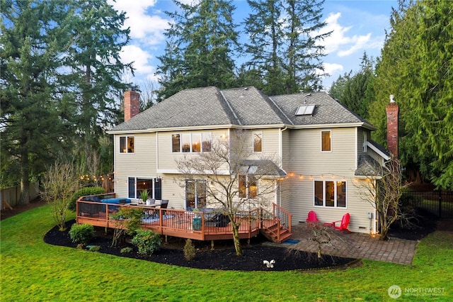 rear view of house featuring a patio, a chimney, a lawn, fence, and a deck