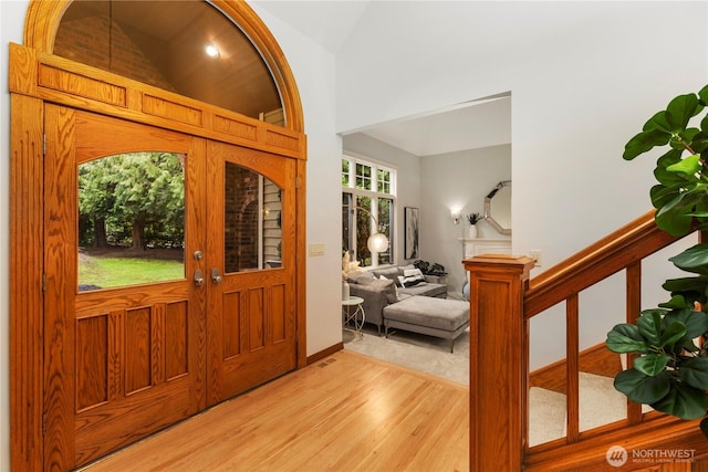 entryway with stairs, french doors, vaulted ceiling, and light wood-style flooring