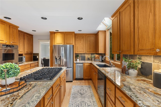 kitchen with tasteful backsplash, brown cabinets, light stone countertops, stainless steel appliances, and a sink