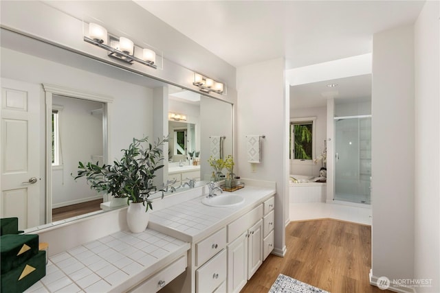 bathroom featuring a garden tub, a shower stall, vanity, and wood finished floors