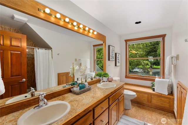 bathroom featuring double vanity, a sink, and toilet