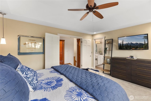 bedroom with light carpet, a ceiling fan, and ensuite bathroom