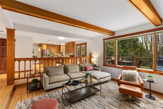 living room with light wood finished floors, a wealth of natural light, beam ceiling, and ornate columns