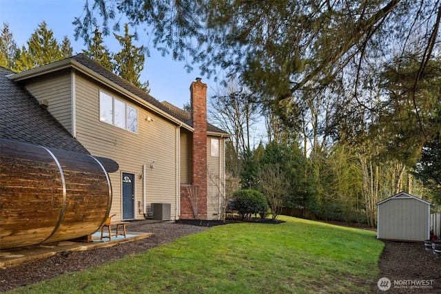 view of yard featuring fence, an outdoor structure, central AC unit, and a storage unit