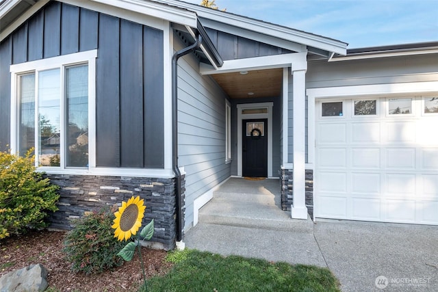 property entrance with board and batten siding, stone siding, and a garage