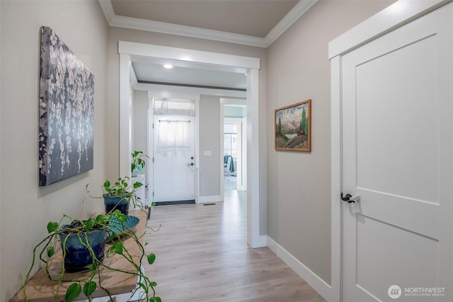 corridor featuring light wood-type flooring, crown molding, and baseboards