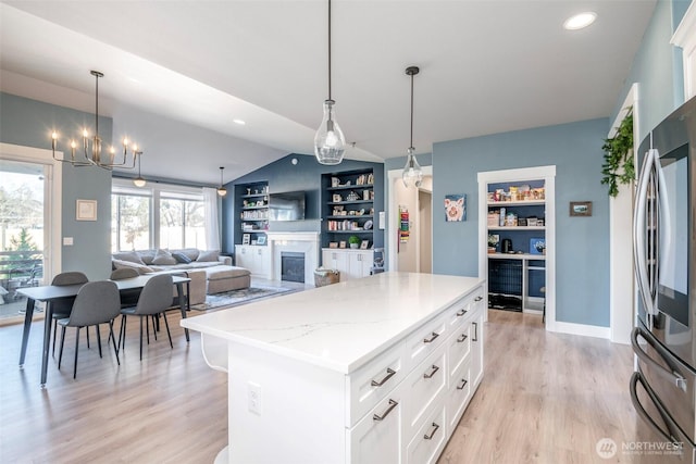 kitchen with built in shelves, lofted ceiling, light wood-style flooring, smart refrigerator, and a glass covered fireplace