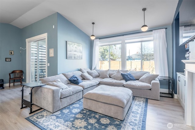 living area featuring lofted ceiling, baseboards, and light wood finished floors