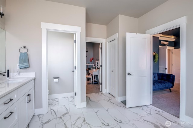 full bathroom featuring toilet, vanity, baseboards, marble finish floor, and a closet