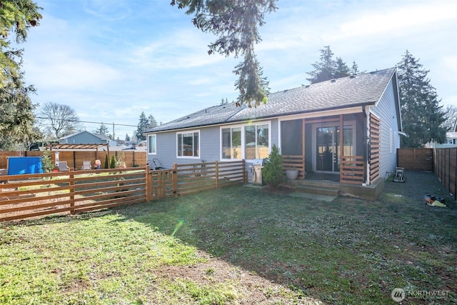 rear view of property with entry steps, a yard, a shingled roof, and a fenced backyard