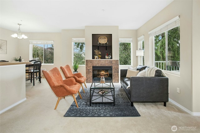 carpeted living room with an inviting chandelier, baseboards, and a tile fireplace