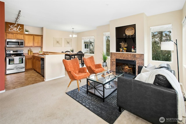 living room with a tiled fireplace, an inviting chandelier, and light carpet