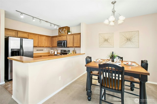 kitchen with pendant lighting, light colored carpet, brown cabinets, and stainless steel appliances