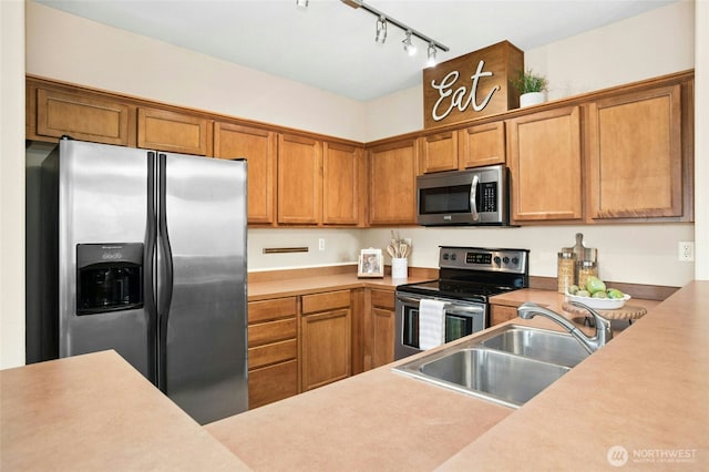 kitchen featuring light countertops, brown cabinets, appliances with stainless steel finishes, and a sink