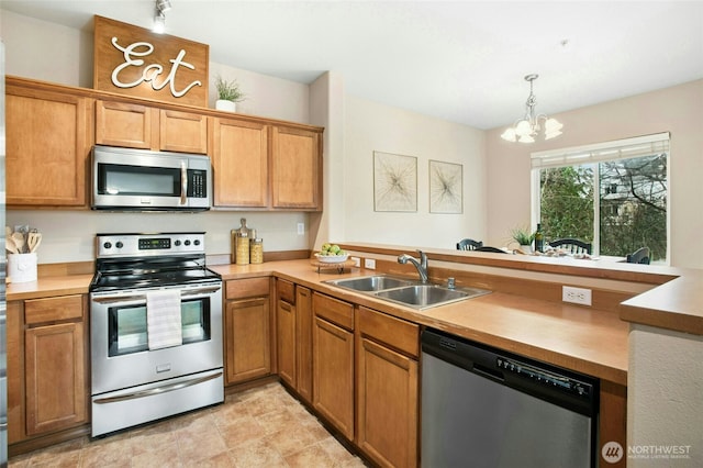 kitchen featuring a peninsula, a sink, hanging light fixtures, light countertops, and appliances with stainless steel finishes