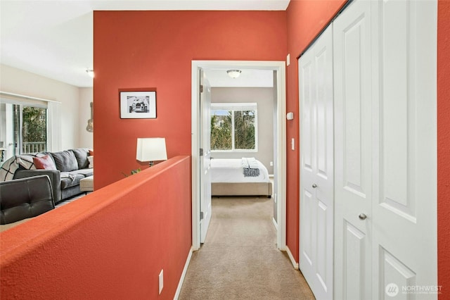 corridor featuring baseboards and light colored carpet