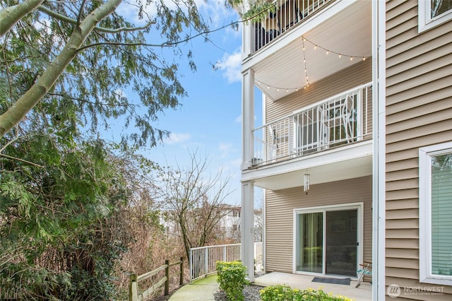 view of side of property with a patio, a balcony, and fence