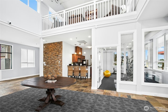 entrance foyer featuring a wealth of natural light, baseboards, and a towering ceiling