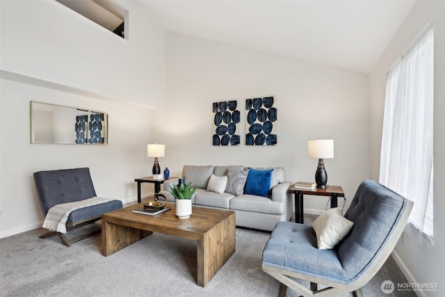 carpeted living area with a healthy amount of sunlight, vaulted ceiling, and baseboards