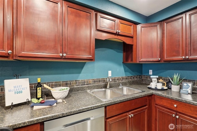 kitchen with dark countertops, a sink, and stainless steel dishwasher