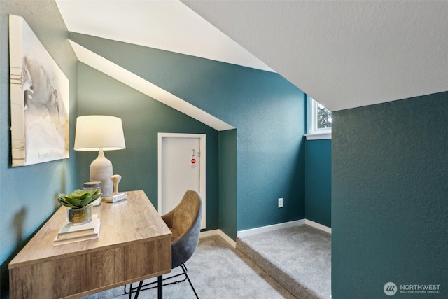 office area featuring carpet floors, lofted ceiling, baseboards, and a textured wall