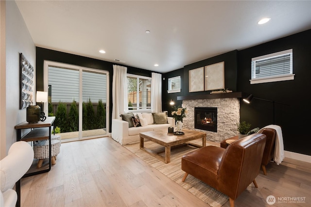 living area featuring light wood-style floors, recessed lighting, a fireplace, and baseboards