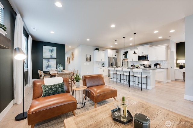 living area with recessed lighting, visible vents, and light wood-style flooring