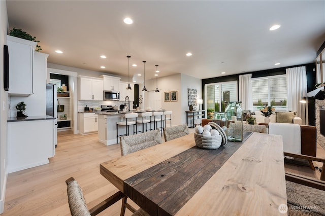 dining space featuring a fireplace, light wood-style flooring, and recessed lighting