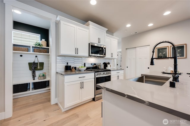 kitchen with appliances with stainless steel finishes, a sink, and white cabinets