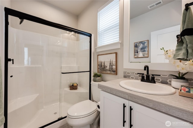 bathroom featuring toilet, a stall shower, vanity, and visible vents