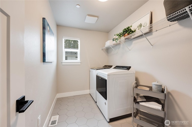 laundry room featuring light tile patterned flooring, laundry area, visible vents, baseboards, and washing machine and clothes dryer