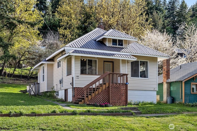 bungalow-style house with a chimney, metal roof, a standing seam roof, a front lawn, and a porch