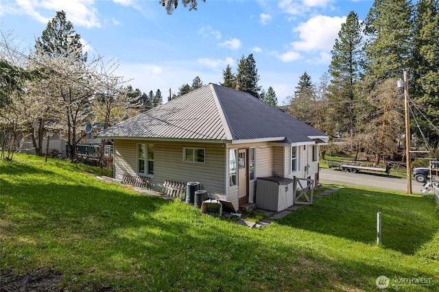 rear view of property featuring metal roof, a yard, and central air condition unit