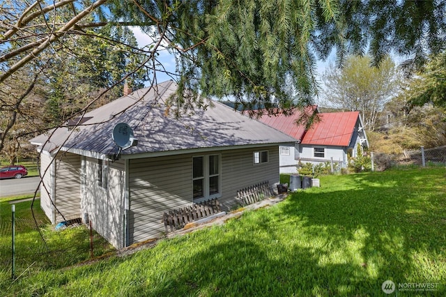 back of house with fence, metal roof, and a lawn