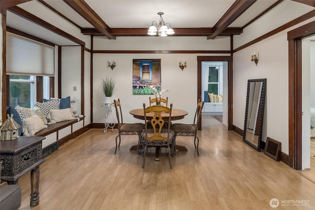 dining area featuring beamed ceiling, light wood-style flooring, and an inviting chandelier