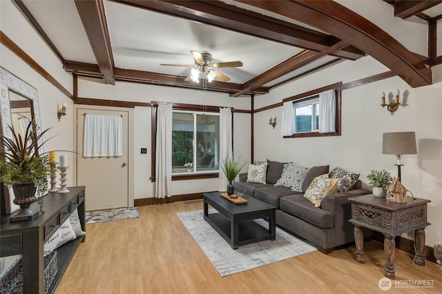 living area featuring a ceiling fan, beam ceiling, baseboards, and light wood finished floors