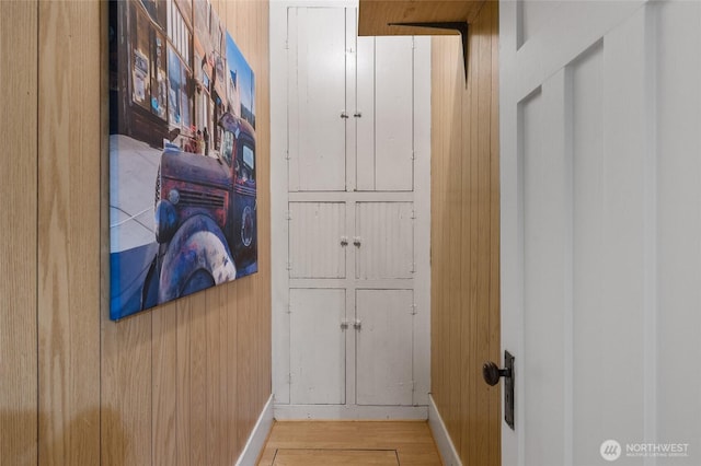 hall with wood walls, baseboards, and wood finished floors