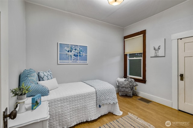 bedroom featuring baseboards, visible vents, and wood finished floors