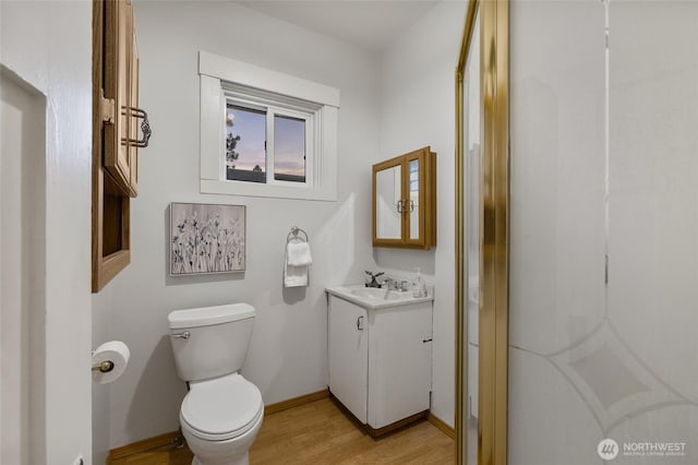 bathroom with baseboards, vanity, toilet, and wood finished floors