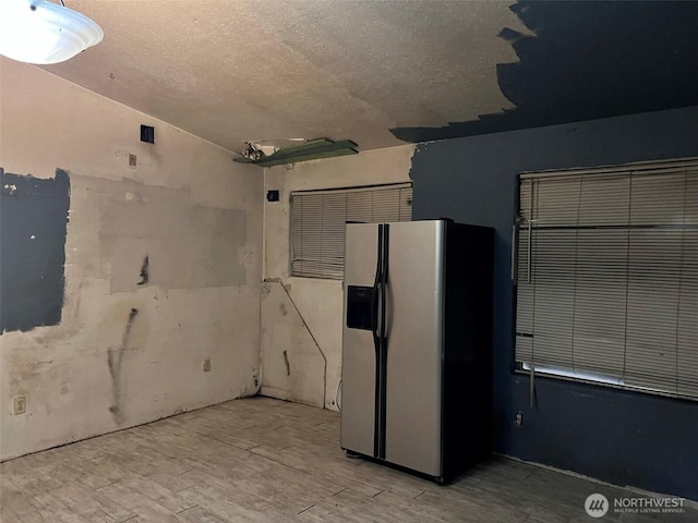 interior space featuring a textured ceiling, stainless steel refrigerator with ice dispenser, and light wood-style flooring